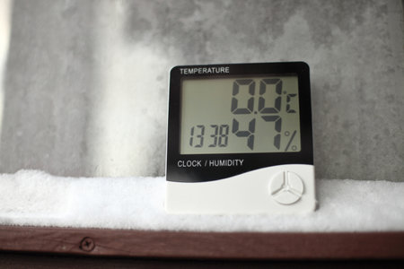 Measurement of the temperature and humidity, thermometer and hygrometer on a window with snow on the background of frozen glassの写真素材