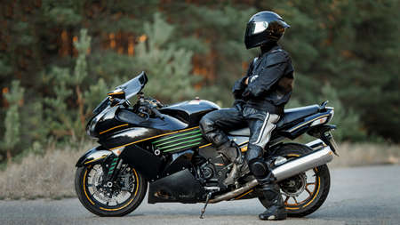 Biker in a helmet and leather protective equipment sits on a motorcycle, a sporty fast motorcycleの写真素材