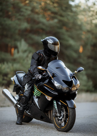 Handsome motorcyclist wear leather jacket and holding helmet on the roadの写真素材