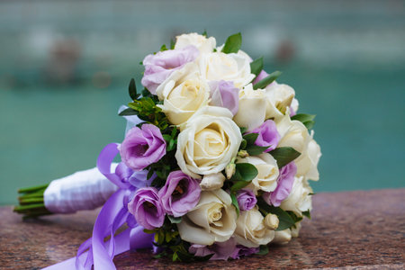 Beautiful wedding bouquet of natural flowers on a blurred background lies on graniteの写真素材