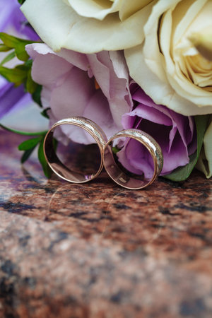 Wedding rings on granite stand against the background of a beautiful bouquet of flowersの写真素材