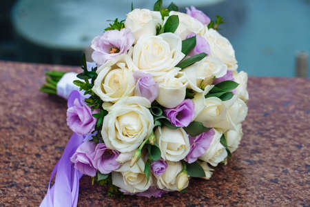 Beautiful wedding bouquet of natural flowers on a blurred background lies on graniteの写真素材