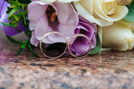 Wedding rings on granite stand against the background of a beautiful bouquet of flowersの写真素材