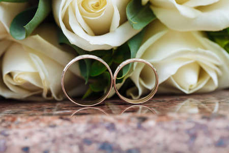 Wedding rings on granite stand against the background of a beautiful bouquet of flowersの写真素材