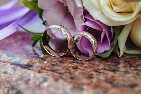 Wedding rings on granite stand against the background of a beautiful bouquet of flowersの写真素材