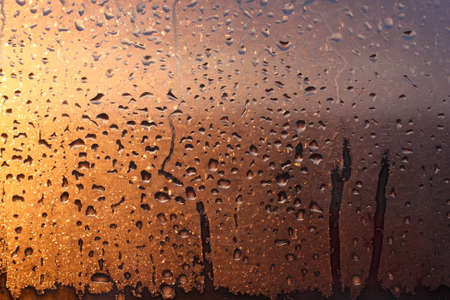 Frozen drops of condensation on a transparent glass window in the winter season with natural sunlight through the glass, high humidity, temperature difference, natural backgroundの写真素材