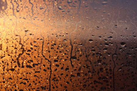 Frozen drops of condensation on a transparent glass window in the winter season with natural sunlight through the glass, high humidity, temperature difference, natural backgroundの写真素材