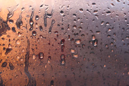 Frozen drops of condensation on a transparent glass window in the winter season with natural sunlight through the glass, high humidity, temperature difference, natural backgroundの写真素材