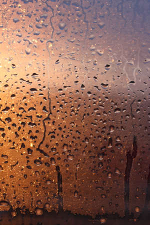 Frozen drops of condensation on a transparent glass window in the winter season with natural sunlight through the glass, high humidity, temperature difference, natural backgroundの写真素材