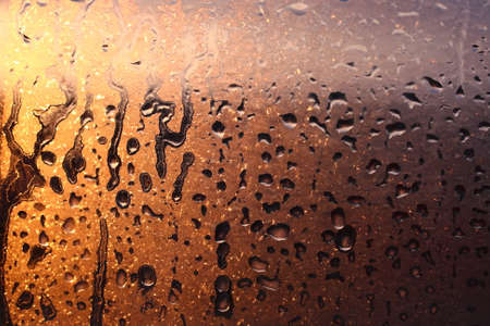 Natural background of condensation of water on a window glass with high air humidity, large drops dripping. Natural sunlight through glass. High humidityの写真素材