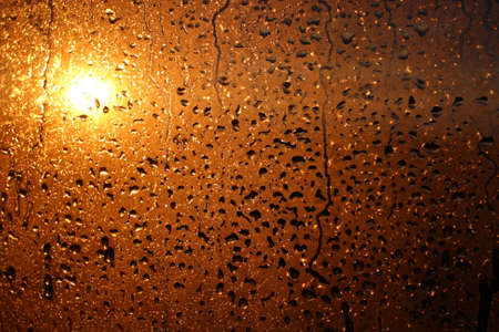 Natural background of condensation of water on a window glass with high air humidity, large drops dripping. Natural sunlight through glass. High humidityの写真素材