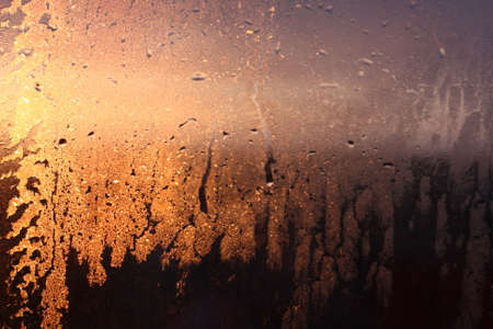 Frozen drops of condensation on a transparent glass window in the winter season with natural sunlight through the glass, high humidity, temperature difference, natural backgroundの写真素材