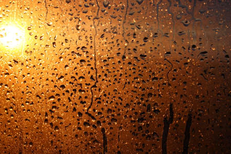 Frozen drops of condensation on a transparent glass window in the winter season with natural sunlight through the glass, high humidity, temperature difference, natural backgroundの写真素材