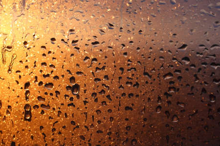 Frozen drops of condensation on a transparent glass window in the winter season with natural sunlight through the glass, high humidity, temperature difference, natural backgroundの写真素材