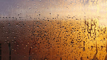 Horizontal natural background with water drops on the window with sunbeams, condensation on the glass with dripping dropsの写真素材