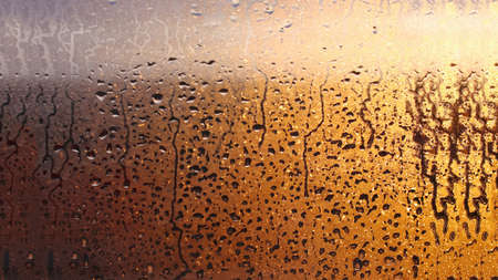 Horizontal natural background with water drops on the window with sunbeams, condensation on the glass with dripping dropsの写真素材