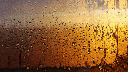 Horizontal natural background with water drops on the window with sunbeams, condensation on the glass with dripping dropsの写真素材
