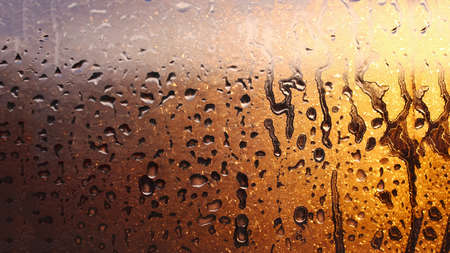 Drops of condensate on the sweaty glass window. Cold foggy glass. Wet window background, texture condensation with dripping dropsの写真素材