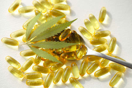 Cannabis oil capsule concept, CBD oil capsules and hemp leaves. Macro close up of capsules of biological and ecological hemp plant herbal pharmaceuticalの写真素材