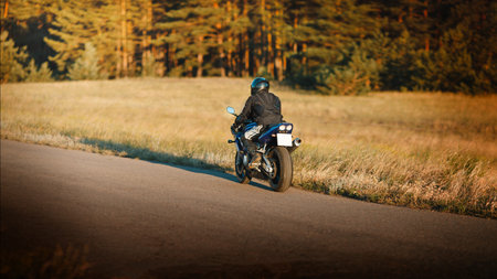 Biker in a protective suit with a helmet. Motorcyclist in a helmet and leather jacket rushes along...