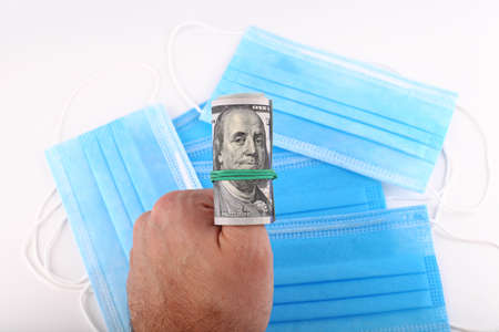 One hundred dollars in hand against the background of a medical mask from coronavirusの写真素材