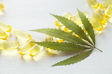 CBD oil pills. Group of transparent CBD cannabidiol capsules and hemp leaves on white background. Organic dietary supplements conceptの写真素材