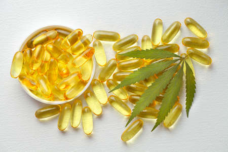 Medical cannabis products, leaf, capsules CBD oil on white background. Pharmaceutical gelatin softgels with biological plant herbal. Organic dietary supplements conceptの写真素材