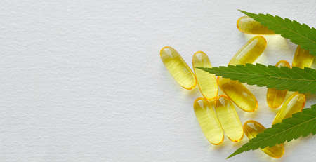 Medical cannabis products, leaf, capsules CBD oil on white background. Pharmaceutical gelatin softgels with biological plant herbal. Organic dietary supplements conceptの写真素材