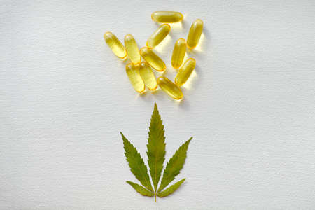 CBD oil pills. Group of transparent CBD cannabidiol capsules and hemp leaves on white background. Organic dietary supplements conceptの写真素材