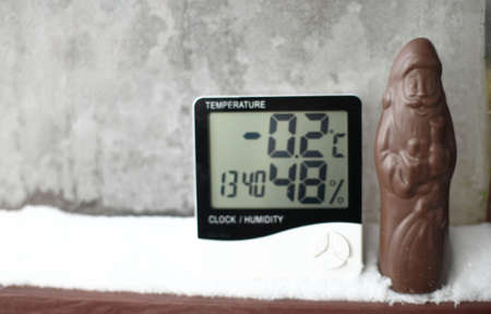 Humidity indicator is displayed on hygrometer installed in the snow next to the chocolate Santa Claus. Picture of an electronic device for testing air temperature and humidityの写真素材