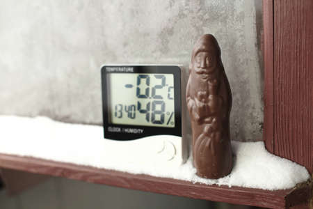 Humidity indicator is displayed on hygrometer installed in the snow next to the chocolate Santa Claus. Picture of an electronic device for testing air temperature and humidityの写真素材