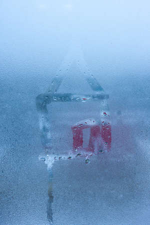 Close-up of drawing of house of condensation on sweaty window pane. hand draw house on foggy windowの写真素材