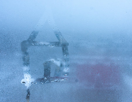 Close-up of drawing of house of condensation on sweaty window pane. hand draw house on foggy windowの写真素材
