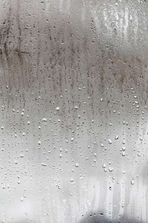Condensation on glass with drops flowing down, Vertical natural background, humidity and foggy blank. outside, bad weather, rainの写真素材