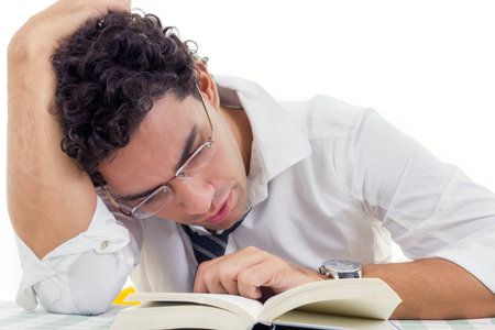 sleepy and tired adult man with glasses in white shirt and tie sitting with book