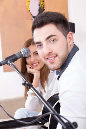 man in white shirt playing guitar and singing to a cute girlの写真素材