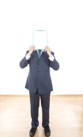 Businessman in suit holding a blank white board instead of his head. Male hands holding a blank white panel on white backgroundの写真素材