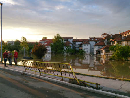 flooded city with view of road and observers on side, flood and disaster in town Obrenovac in Serbia, damaged houses and property, state or condition after terrible flood, destroyed and abandoned cityの写真素材