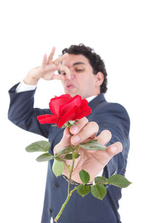 man in suit throws a rose and gives it to the camera while the other hand holds a stuffy nose with his hand because of the smell of flowers, isolated on white backgroundの写真素材