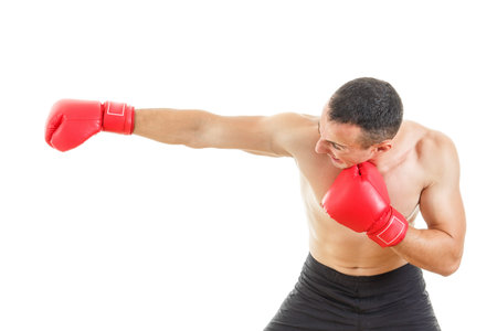 Side view of muscular male boxer hitting straight against a white background