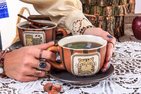 Girl holding hot cup of tea on wooden table with doily in old vintage houseの写真素材