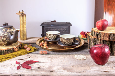cups of tea on old wooden table, with apples, nuts and tea pot next to them.の写真素材
