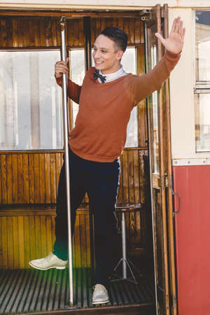 vintage photo of happy smiling man in wagon train or tram holds rod  and waving , fashion retro compositionの写真素材