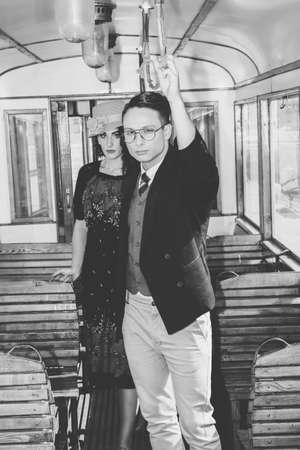 old time modern man with glasses in suit in a wagon train with a woman behind him, vintage retro fashion photoの写真素材