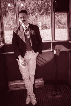 man with mustache in suit posing in a old wooden wagon train or tramの写真素材