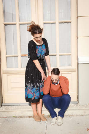 pretty young woman comforting depressed man in front of the house in the stairwellの写真素材