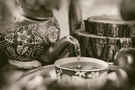 Pouring tea from kettle in retro vintage compositionの写真素材
