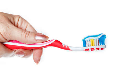 Hand holding red toothbrush with blue two color toothpaste on light surface. Photo of dental hygiene and health maintenance. Object isolated on white background without shadowsの写真素材