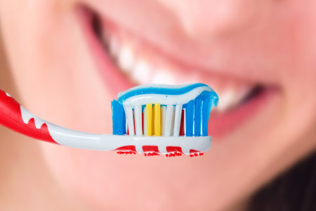 Red toothbrush with blue two color toothpaste with human smile background. Photo of dental hygiene...