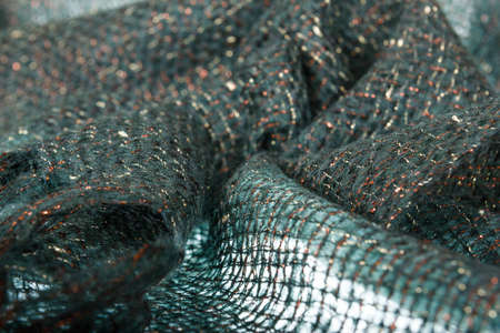 Fragment of wool handmade scarf with golden threads in knitted concept backgroundの写真素材